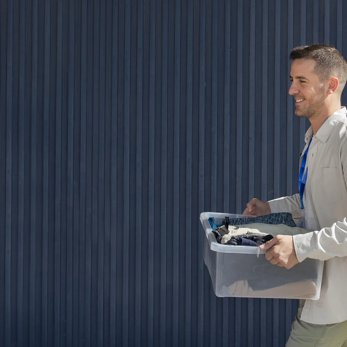 A man carrying a laundry basket across a dark panelled interior