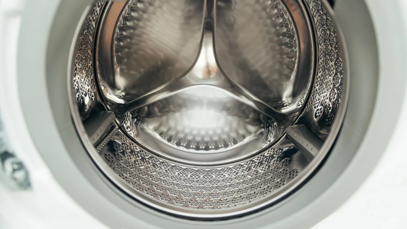 The polished stainless steel drum inside a modern commercial washing machine