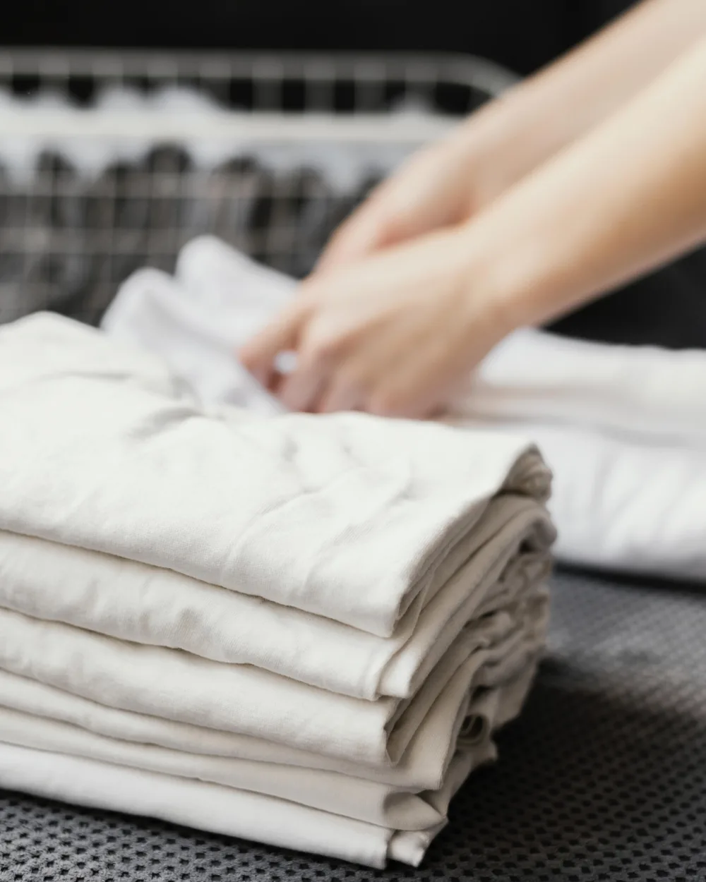 A neat stack of freshly folded white linen on a folding counter