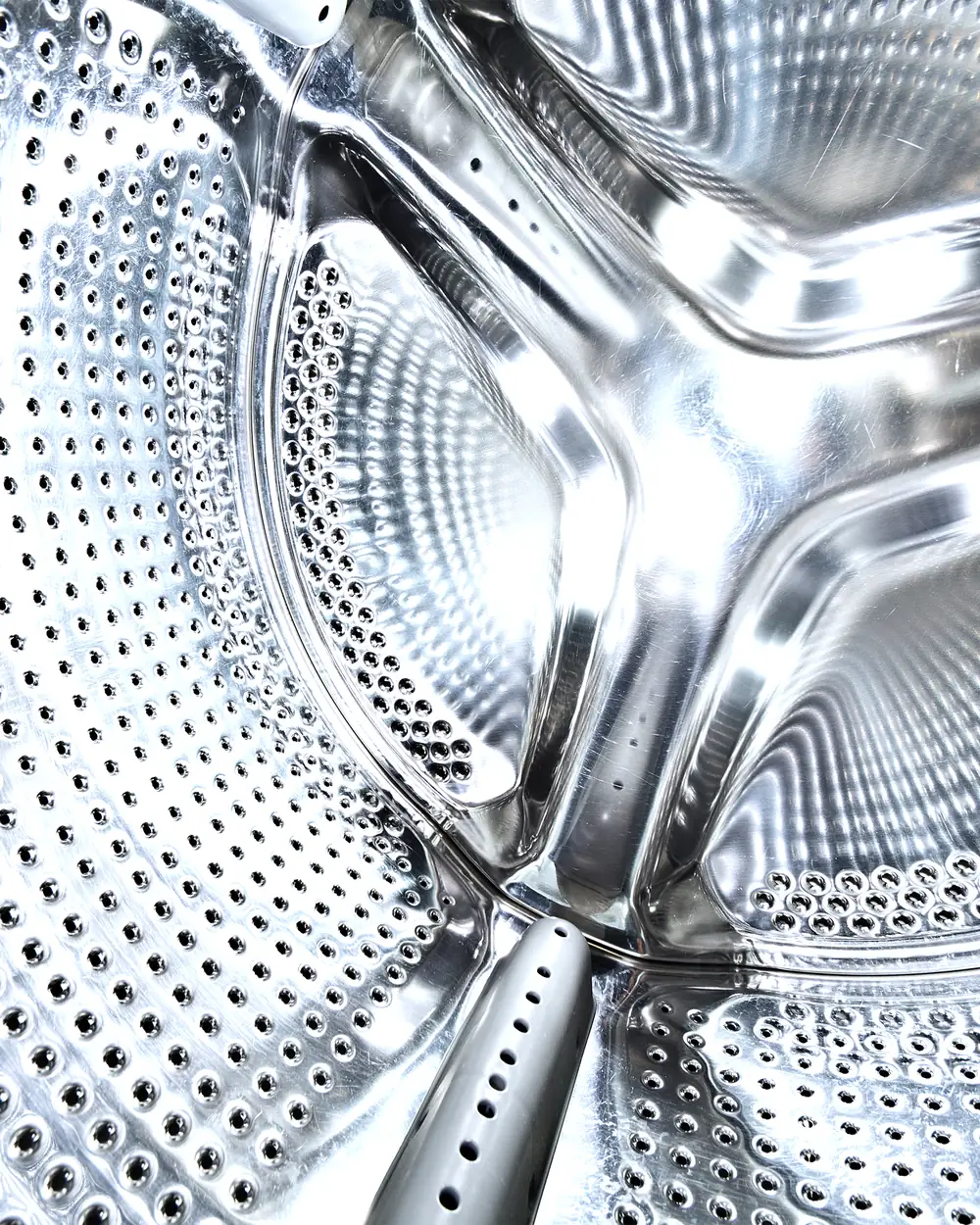 The perforated stainless steel drum inside a commercial washing machine