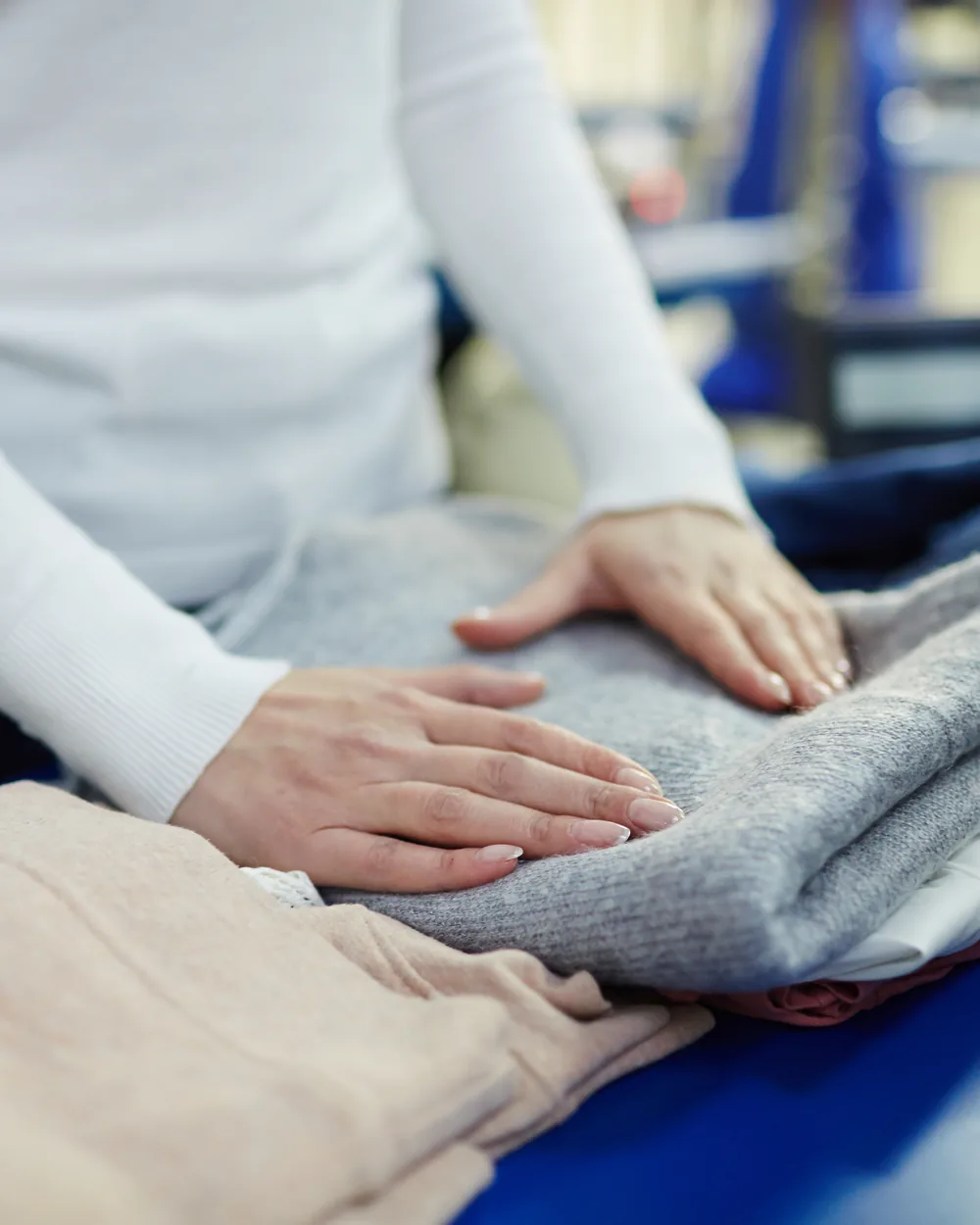 An attendant folding a garment carefully on a pressing table